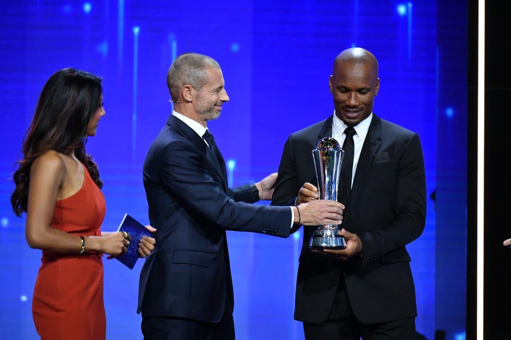 Didier Drogba receiving his award from Aleksander Ceferin's hands.