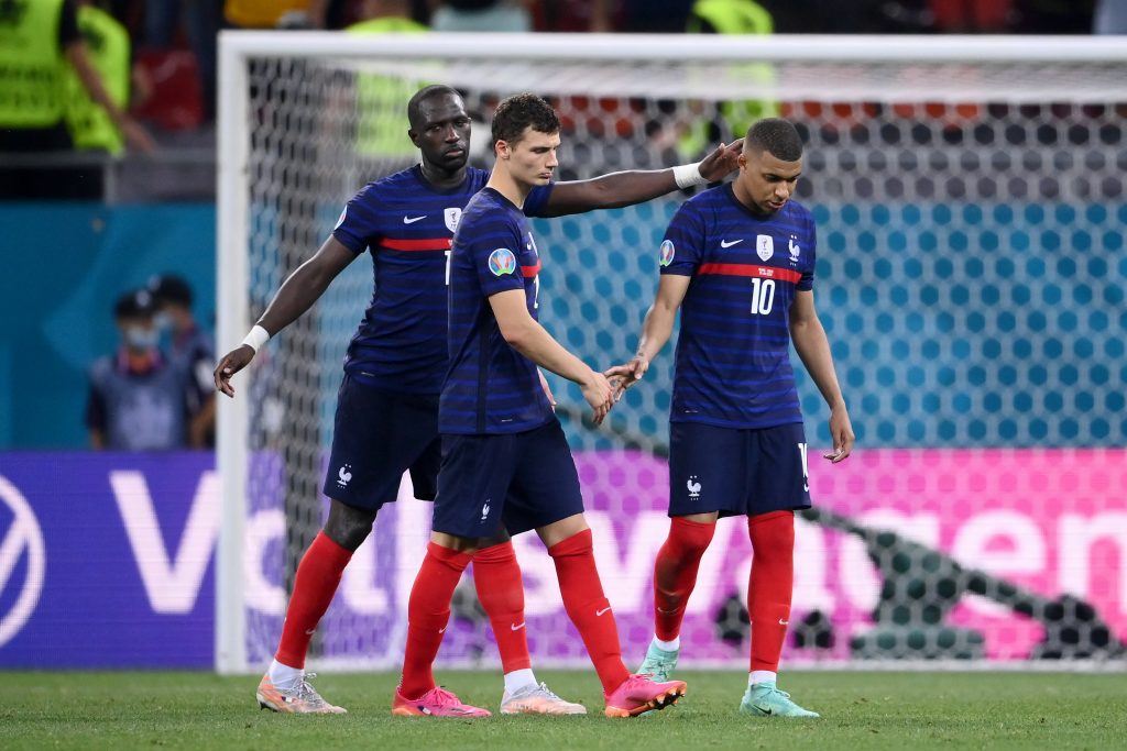 Kylian Mbappé being consoled by his teammates.